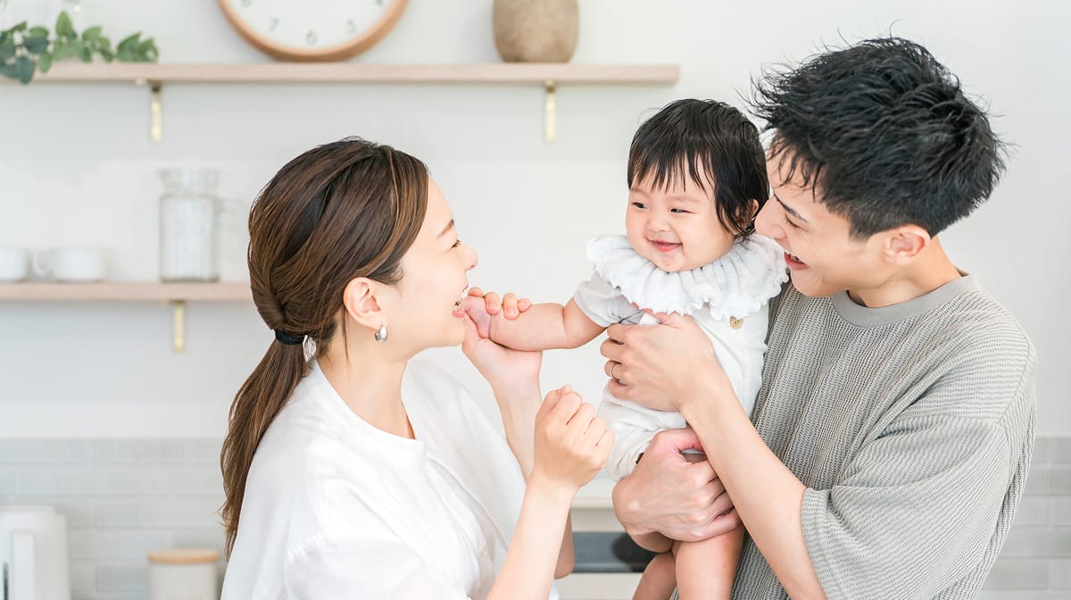 赤ちゃんを抱っこして笑い合う家族の写真